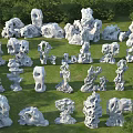 Various Unique Shaped White Stones Scattered On Green Grass With Trees