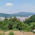 Garden Landscape Wooden Deck Circular Stone Features Railing Trees Distant Mountains City View Clear Sky