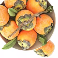 Fresh Ripe Persimmons in Ceramic Bowl with Green Leaves and Wooden Branch