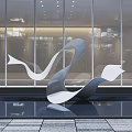 Sleek Metallic Sculpture With Flowing Curved Design In Indoor Lobby With Water Pool Reflection