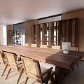 Serene Lounge Area Featuring Long Wooden Table Rattan Chairs And Large Windows With Natural Light
