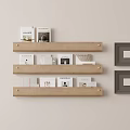 Photo Wall Featuring Beige Wall Three Wooden Shelves Displaying Books And Hanging Dark Frames