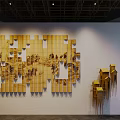 Yellow Wooden Panel Art Installation With Landscape Patterns And Small House Structures In Indoor Lighting