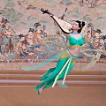 Woman in Green Traditional Costume Dancing with Pipa in Front of Dunhuang Murals