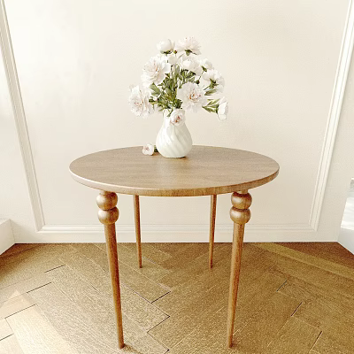 Round Wooden Table Featuring White Vase With Flowers Against Light Colored Wall And Wooden Floor 3d model
