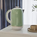 Green Electric Kettle On White Cabinet With Cup And Saucer In Indoor Setting