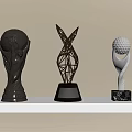 Golden Trophies With Football Golf Ball And Metal Structure Designs On White Shelf