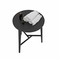 White Rolled Bath Towels With Black Soap Dispensers And Small Flower Decor On Black Table