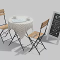 Round Table with Wooden Chairs Checkered Tablecloth Cups Open Book and Chalkboard Sign