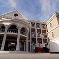 Elegant Classical Building with Red Bricks White Walls Porch Columns Autumn Trees Lawn and Bench