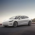 White Tesla Model 3 Electric Car Parked On Open Road With Mountain Sky View