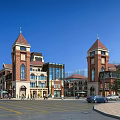 Commercial Street Red Brick Buildings With Clock Towers Glass Facades Pedestrians Cars And Blue Sky