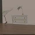 White Chest of Drawers With Gold Accents And Potted Plants Nearby