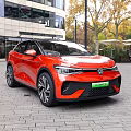 Red Volkswagen ID5 Electric SUV in Urban Setting With Modern Buildings And Trees