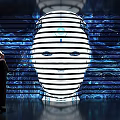 Person Standing Before Large Striped Illuminated Face With Tech Inspired Background Lines 3d model