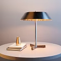 Contemporary Metal Table Lamp Illuminated On White Round Table With Books And Golden Decor