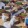 Farm Enclosure With Colorful Fence Sheep Huts Person White Stork And Planter Boxes