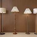Modern Floor Lamps With Various Designs Against Wooden Panel Wall And Natural Light