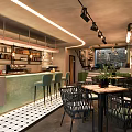 Modern Café Interior Design With Green Counter Black Chairs Checkered Tiles And Potted Plants