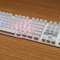 Modern Full Size White Computer Keyboard With RGB Backlit On Wooden Desk