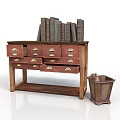 Wooden Drawer Cabinet With Metal Handles Old Books On Top And Metal Trash Bin Beside