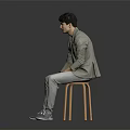 Man Sitting on Wooden Stool Wearing Light Green Blazer Gray Pants and Gray Shoes