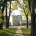 Modern Multistory Office Building With Brick And Glass Exterior Surrounded By Trees Grass Pathway