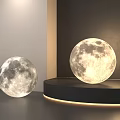 Two Modern Moon Lamps Display On Stand And Floor With Soft Light