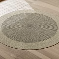 Round Woven Rug With Beige And Dark Gray Concentric Circles On Wooden Floor