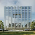Modern Glass Curtain Wall Office Building With Vertical Facade Front Lawn And Trees