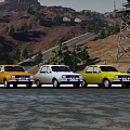 Various Colored Vintage Cars Lined Up On Road With Hills And Tower Background