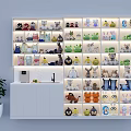 Display Shelf With Various Plush Toys Illuminated Next To White Cabinet And Potted Plant