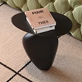 Modern Black Side Table With Stacked Books On Light Carpet Near Green Sofa