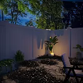 Serene Nighttime Outdoor Space With White Fence Stone Patio Green Plants And Striped Chair