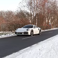 White Porsche Sports Car Parked On Snowy Winter Road With Trees And Snowy Surroundings
