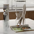 Elegant Decorative Ornament Set Featuring Metallic Vase Transparent Glass Cup And Magazine On Kitchen Countertop