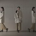 Women In Beige Coats Brown Pants And Black Shoes Against Concrete Wall