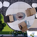 Garden With Circular Stone Patio Round Table Flowers Brown Chairs Surrounding Stones And Blue Blooms