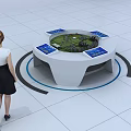 Woman Observing Interactive Sand Table With Circular Design Surrounding Screens And Green Terrain Building Model