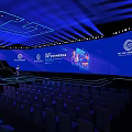 Modern Conference Stage Design With Blue Lighting Large Screens And Arranged Seats Setup