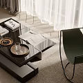 Black coffee table with glass top wooden tray books and green chair in living room