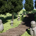 Stone Stepping Path in Garden with Green Lawn Trees Stone Lanterns and Monk Statues