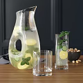Refreshing Lemonade in Glass Pitcher with Lemon Cucumber Slices Mint Leaves Glasses and Nut Bowl
