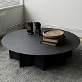Round Black Coffee Table On Gray Rug With Small Sculptures Wooden Tray And Stacked Books