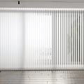 White Vertical Blinds Covering Large Window In Bright Modern Interior With Wooden Floor