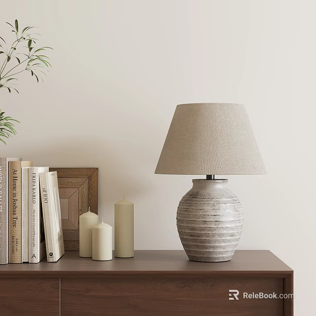 Textured Base Table Lamp With Beige Lampshade On Wooden Shelf Near Books Candles And Plant 3d model 