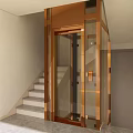 Modern Indoor Elevator With Glass Door And Bronze Frame Near Staircase