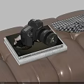 Modern Digital Camera Placed On Photography Book Over Leather Surface With Checkered Scarf