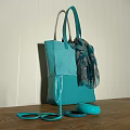 Turquoise Tote Bag With Decorative Scarf On Wooden Surface Against Striped Wall