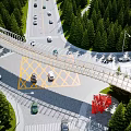 Modern Pedestrian Bridge Over Busy Highway With Green Trees Vehicles And Red Artwork